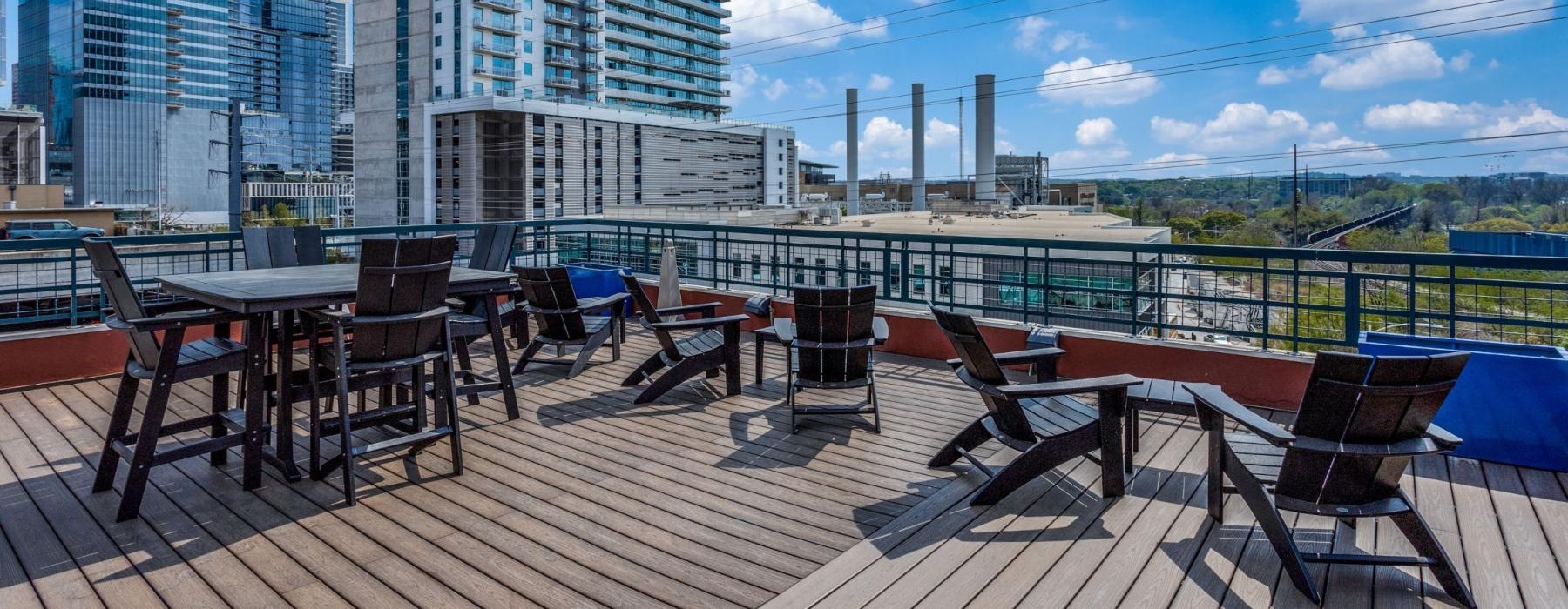 a deck with tables and chairs with tall buildings behind it
